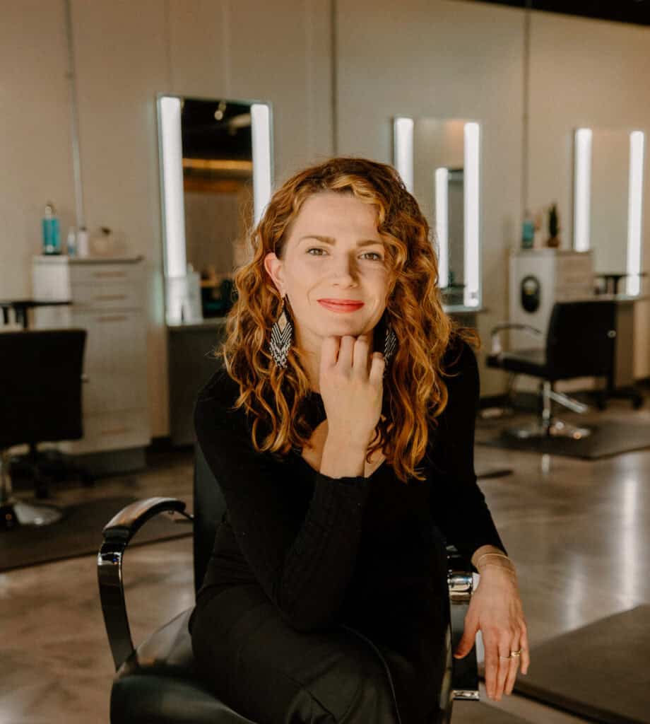 Elegant woman with curly red hair in a modern salon setting.
