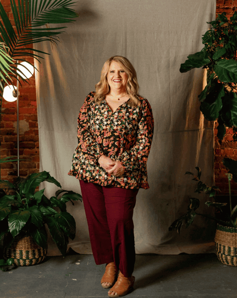 Woman smiling in cozy floral top and maroon pants in Upper Cumberland setting.