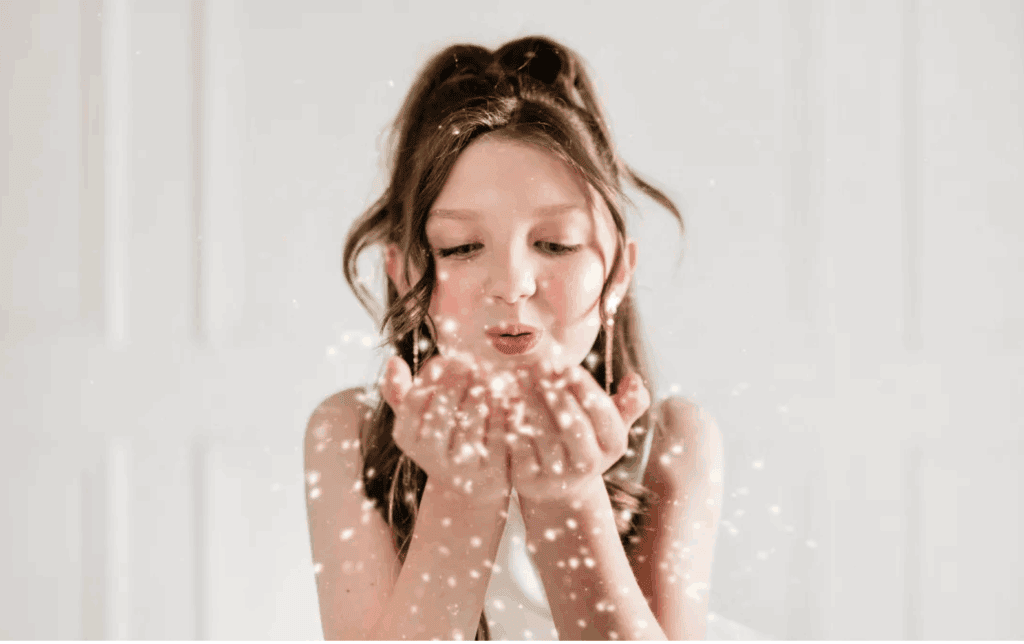 Young girl blowing sparkles, joyful moment, Upper Cumberland lifestyle.