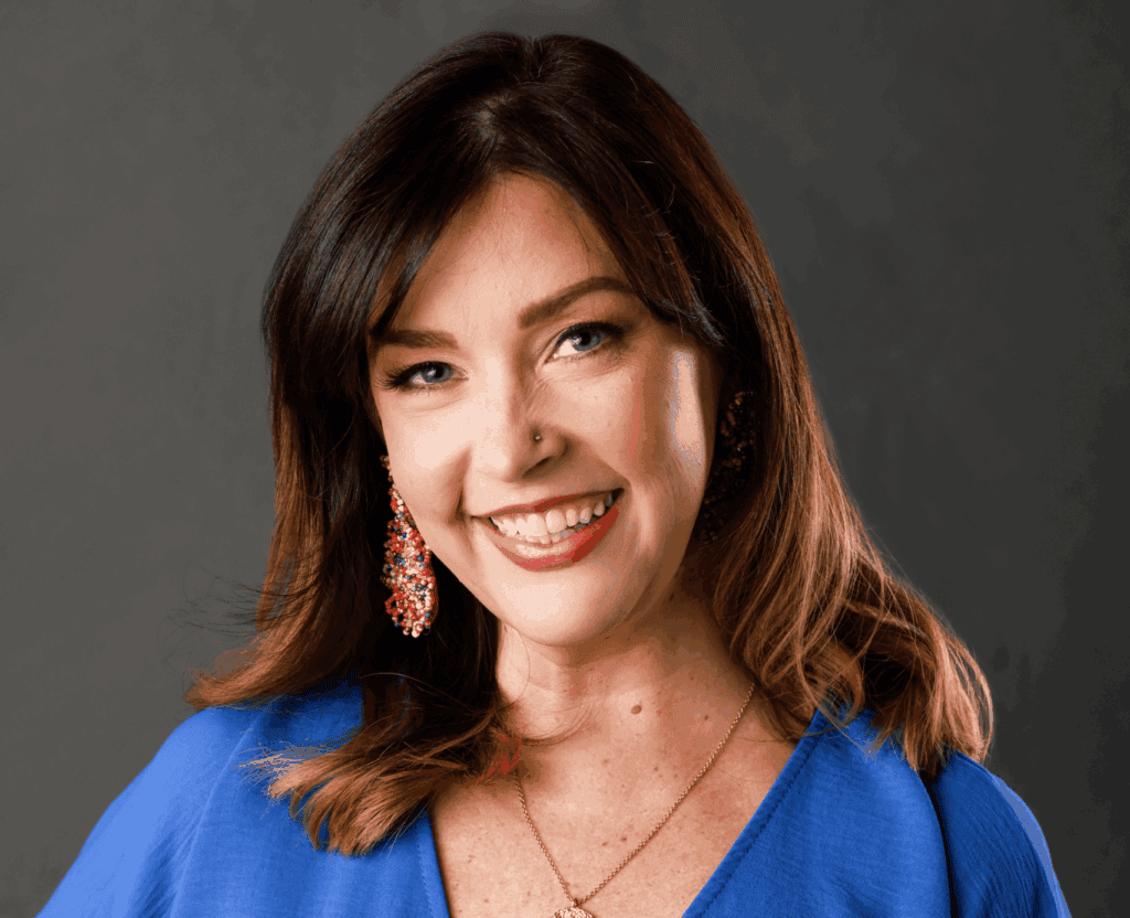 Smiling woman with brown hair and earrings, wearing a blue dress, representing local lifestyle and c.