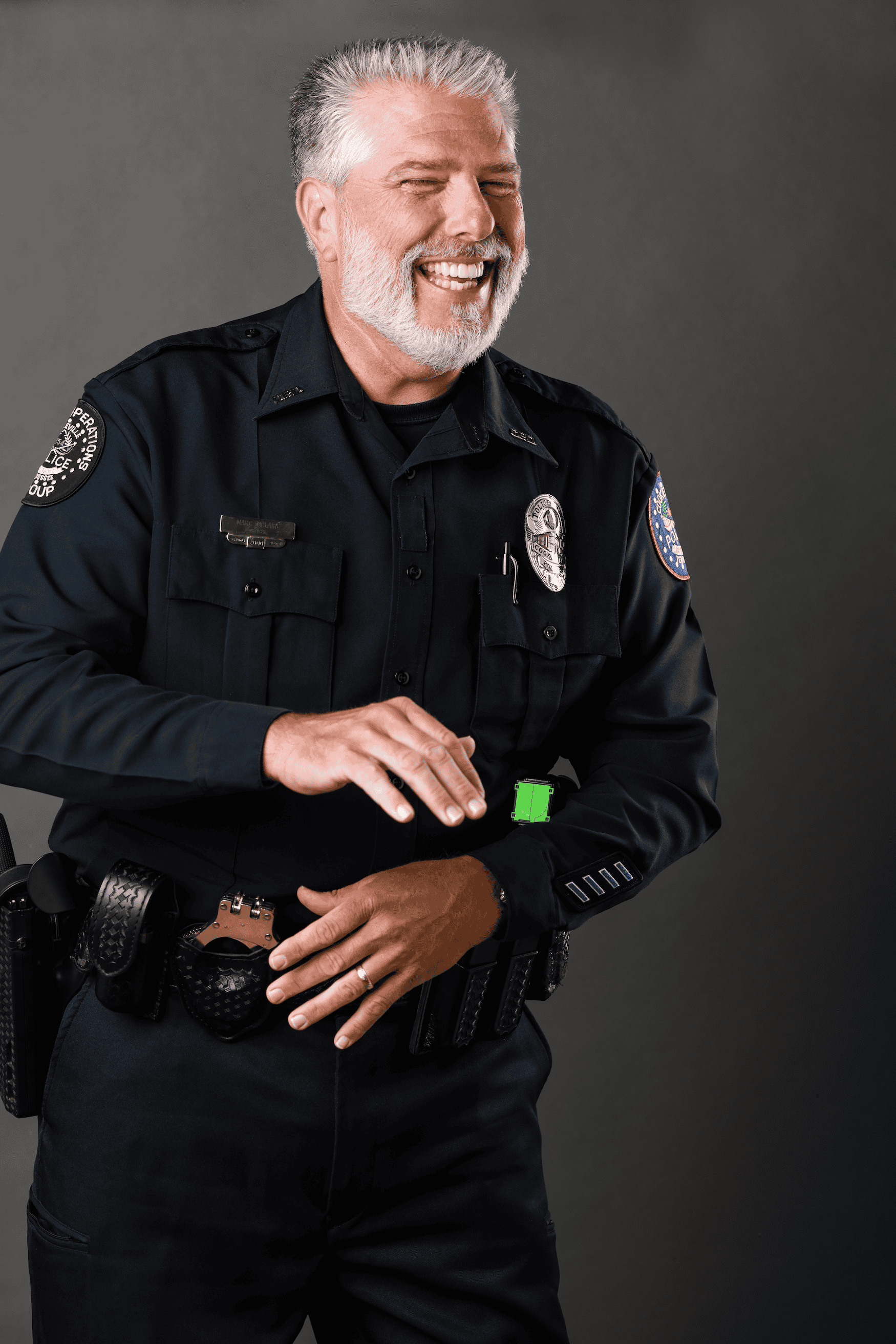 Police officer smiling, wearing uniform with badge and radio.