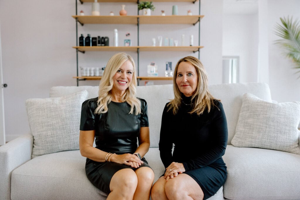 Women sitting on a sofa in a bright, modern living room with minimalist decor.
