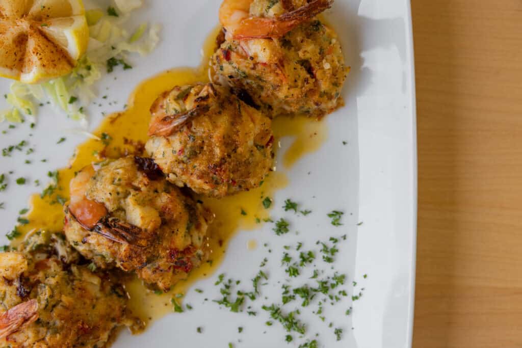 Delicious shrimp and crab cakes with herbs and lemon on a white plate.
