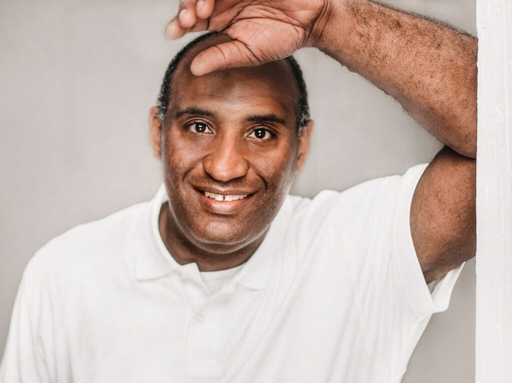 Man smiling with hand on head, casual portrait.