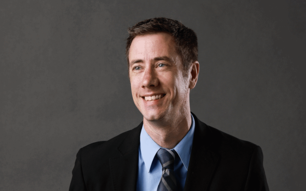 Business professional smiling in a formal suit and tie, representing Upper Cumberland Lifestyle.