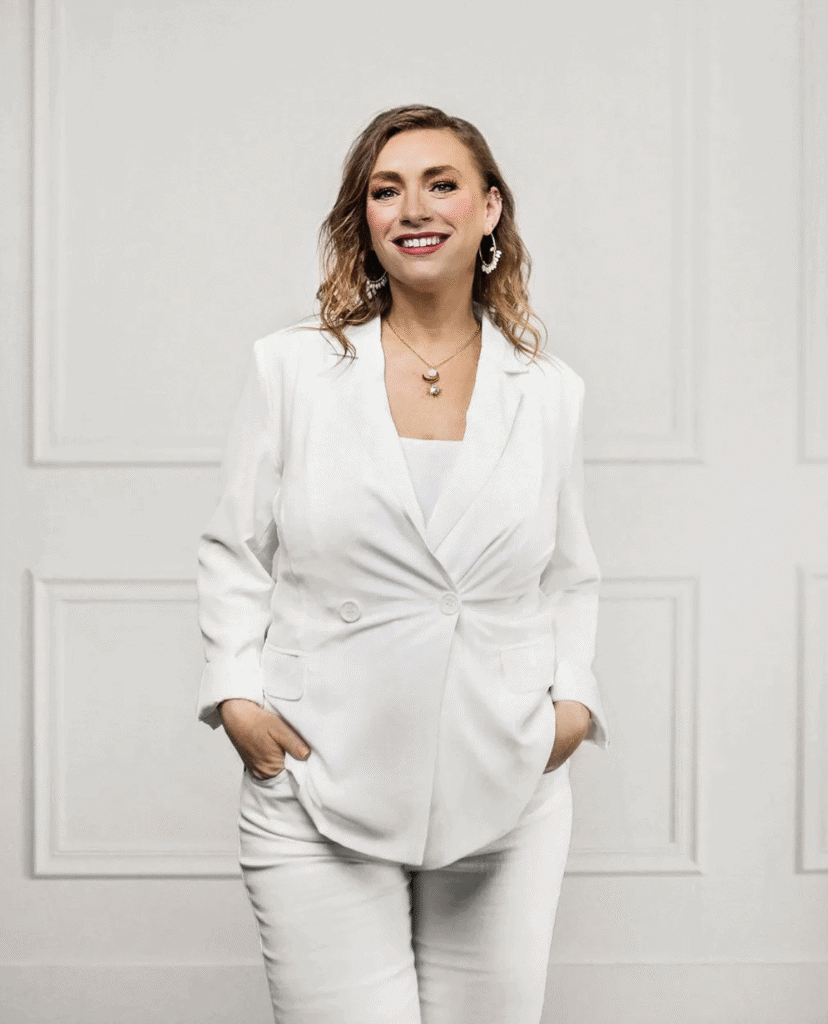 Elegant woman in white business suit smiling confidently.