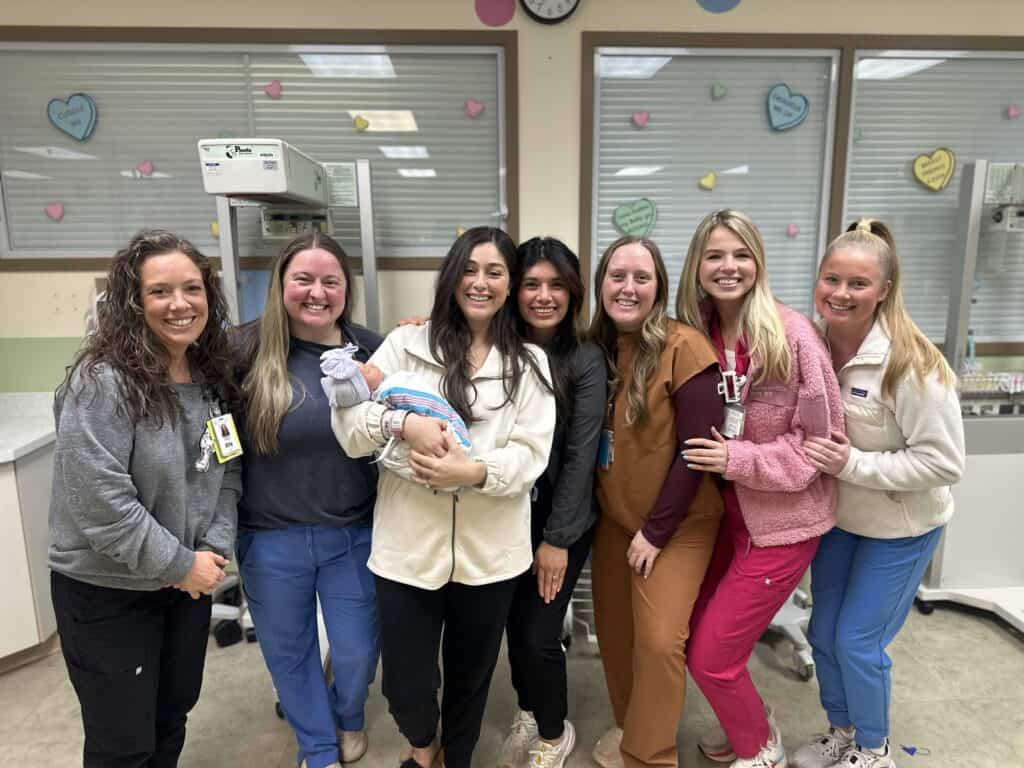 Group of healthcare professionals caring for a newborn baby in a hospital.